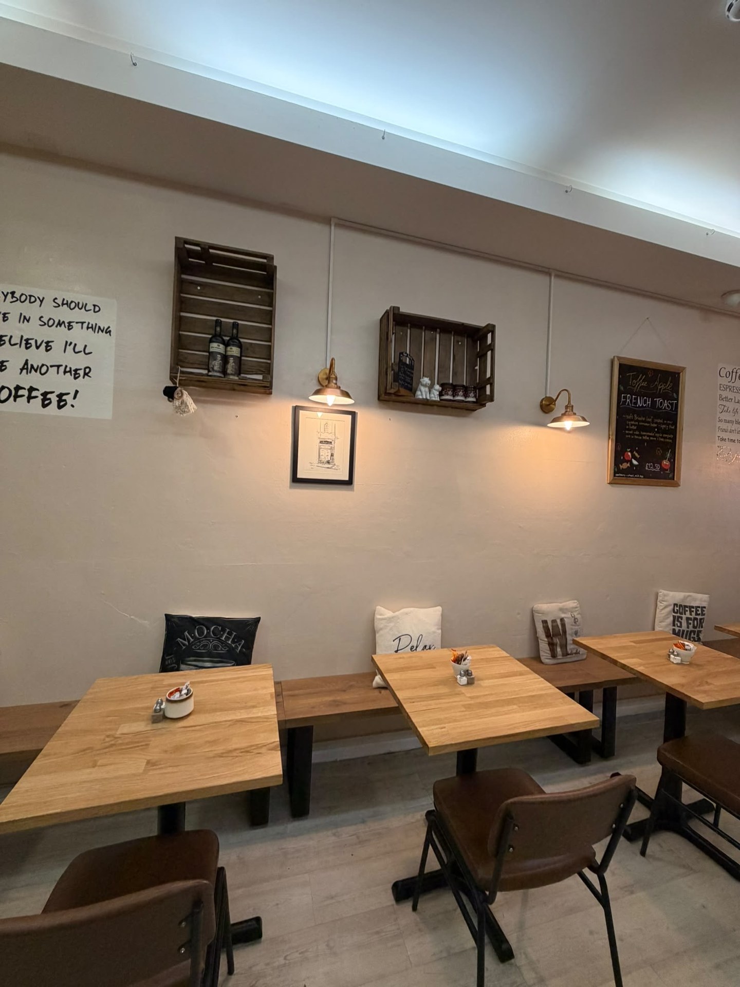 New wooden bench seating with cushions and tables for two
