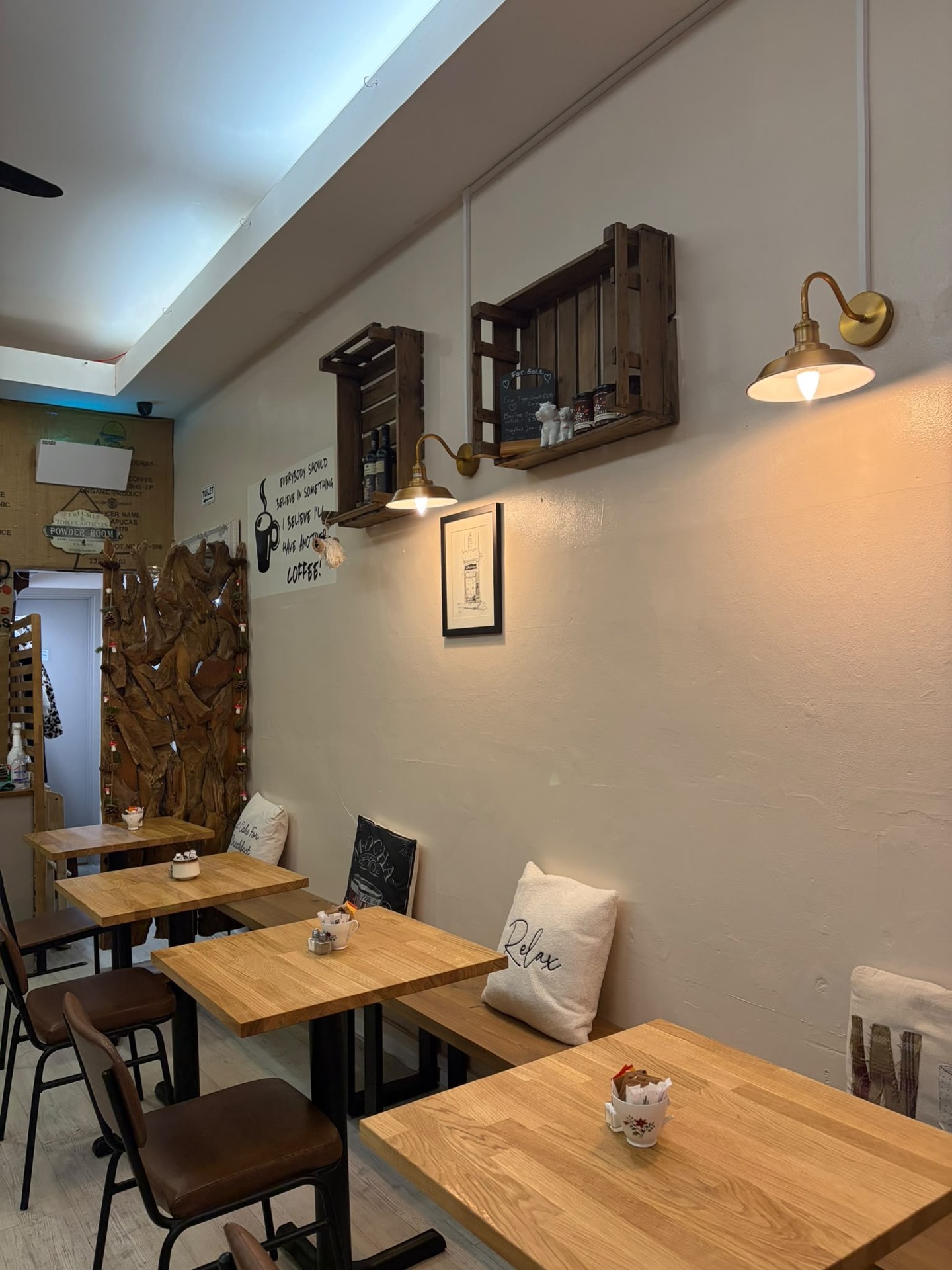 Warm brass wall lights and wooden crate shelves above the new café seating